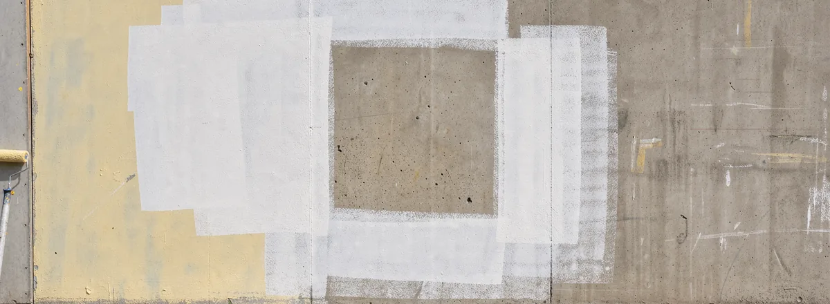 A square unpainted gap remains between pale yellow and chalk-white areas on a hoarding.